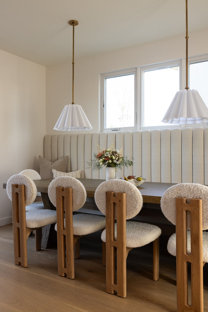 Dining room with wooden table and chairs, beige walls, and large windows.