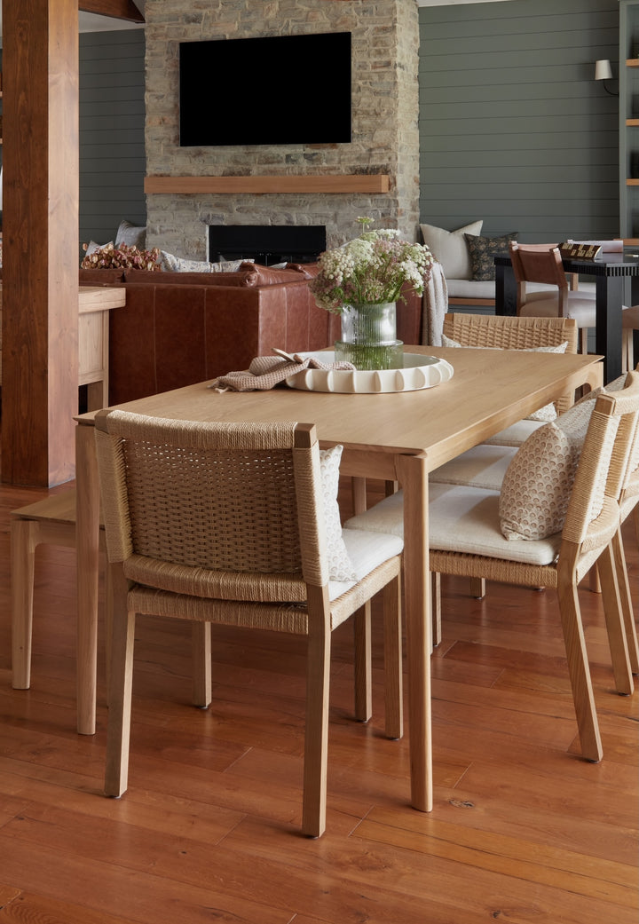 Dining room with wooden table and chairs, floral centerpiece, and stone fireplace.