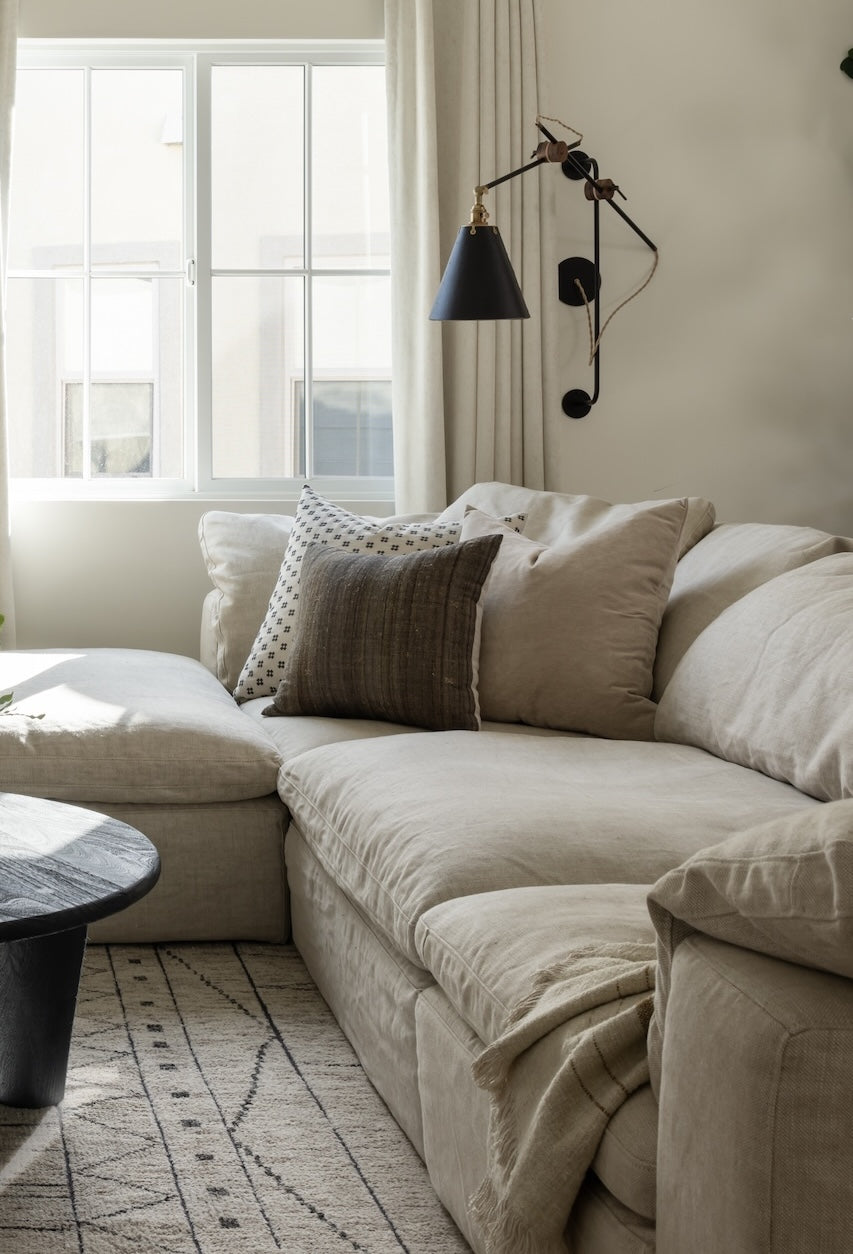 Beige sectional sofa with decorative pillows in a living room setting.